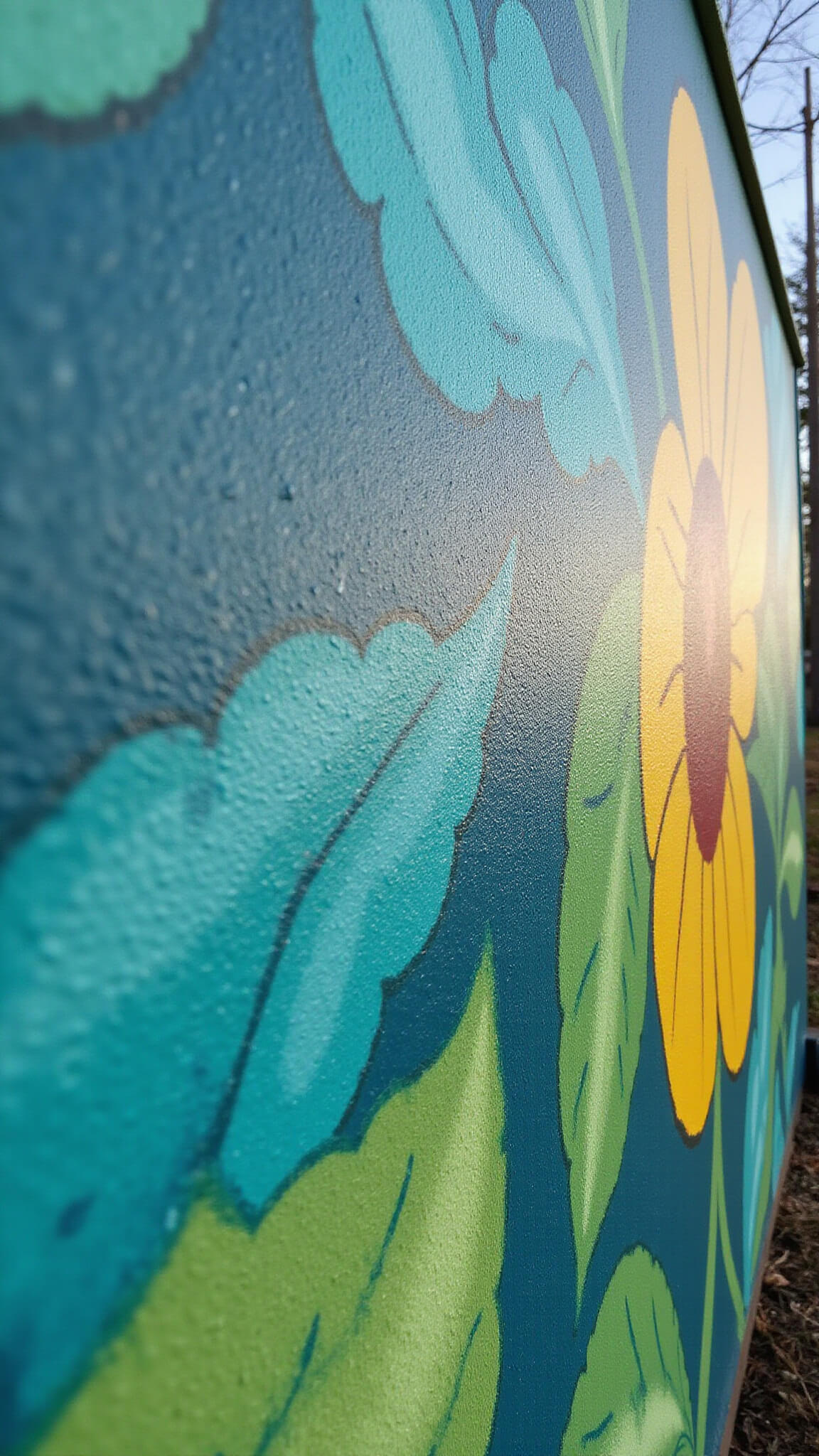 Close-up of a 10x8-foot DIY garden wall mural featuring abstract botanical designs in emerald green, cobalt blue, and sunny yellow, with textured brushstrokes highlighted by late afternoon light.
