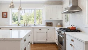 "Antique white kitchen cabinets in a modern farmhouse with natural sunlight streaming through windows, marble countertops, brass hardware and white shaker style creating a warm and cozy atmosphere."